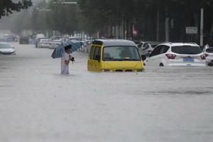 中國河南鄭州強降雨，行人20日涉水通過積水路段。（圖源：互聯網）