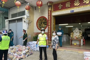 培德精舍副理事長曾碧湄與第十一郡領導給地方受疫情影響生活困難的貧民派發援助品。