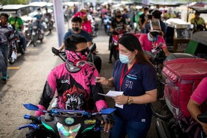 菲律賓15日通報出現首例Lambda變種病毒感染案例。圖為菲國醫護人員向準備接種疫苗的外送員，說明注意事項。（圖源：路透社）