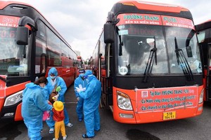 民眾穿著防護服準備搭乘免費班車離開本市返回福安省。