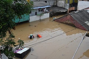 2021年2月8日，印尼雅加達，大雨造成洪水氾濫，一名居民正在撤離。 (圖源：AFP)