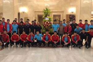 越南男子足球隊在國家主席贈送的花籃旁合影留念。（圖源：VFF）