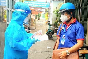 市共青團幹部周進祿（右）與醫護人員討論關於新冠患者居家治療的情況。