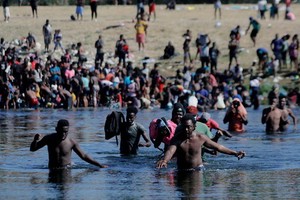 這張9月19日在墨西哥科阿韋拉州阿庫尼亞城拍攝的照片顯示，非法移民走過美墨邊境的里奧格蘭德河，進入墨西哥一側購買食物和生活必需品。 （圖源：新華社）