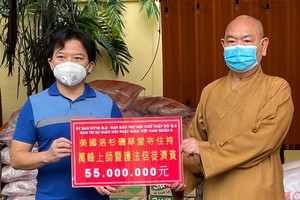 麒麟（左）代表旅美僑胞向釋慧功法師（右）捐贈善款。