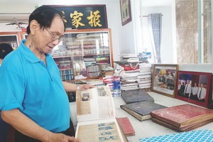 張漢明書畫家在整理剪報冊。