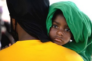 9月25日，在墨西哥阿庫尼亞城的移民收容所，一名來自海地的移民男孩和他的父親排隊向墨西哥移民官員遞交信息。（圖源：新華社）