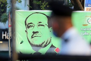 9月16日，在伊拉克巴格達，行人從國民議會候選人的競選海報前走過。（圖源：新華社）