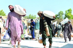 人們在阿富汗坎大哈領取由世界糧食計劃署提供的物資援助。（圖源：新華社）