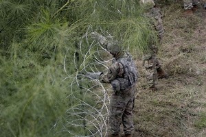 美國士兵在美墨邊境安裝鐵絲網嚴防移民入境。（圖：互聯網）