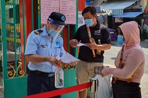 溫陵會館保安員檢查進廟善信的注射疫苗證件。