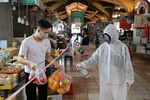 民眾在第一郡濱城市場購物時穿防護服、消毒及 保持安全距離。