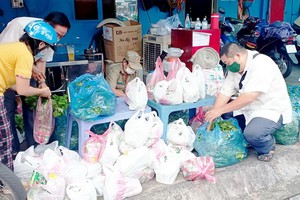 李仁成（右一）向窮人免費贈送必需品。