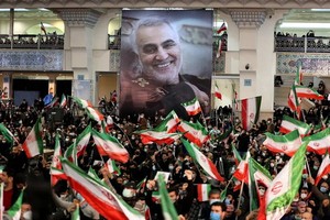 蘇萊曼尼遇襲兩週年，伊朗民眾手持他的肖像畫和伊朗國旗，聚集在首都德黑蘭參與紀念活動。（圖：AFP）