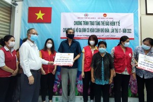 穗城會館理事長盧耀南向第二坊貧困戶代表贈送醫保卡。