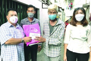 丁文森（左一）與坊領導向窮苦華人（右二）贈送禮物。