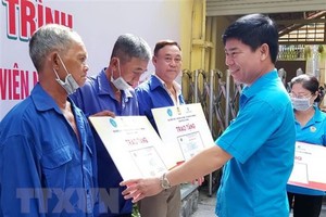 市勞動聯團副主席范志心代表市勞動聯團向貧困摩的、網約車司機贈送醫保卡。（圖：越通社）