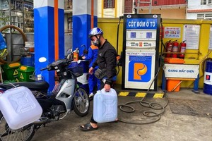 一名河內市民在加油站購買汽油時用塑料桶盛裝汽油。（圖：互聯網）