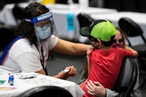 圖為 2021年12月12日，在加拿大多倫多的一處新冠疫苗接種中心，接種員準備為一名兒童接種疫苗。（圖：新華社）