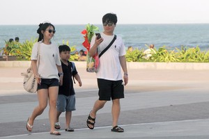 一個三口之家小家庭的韓國遊客在遊逛芽莊海邊風光。（圖：中宇）