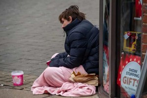 一名無家可歸者坐在人行道上。（圖：互聯網）