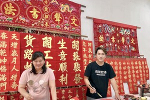 梁岱媮与梁朝铭正在挥毫挥春。