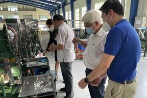 红心公司经理刘成发(右)引导本市纺织品成衣协会主席范春鸿参观公司车间。