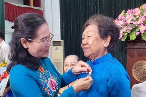 市委副书记、市人民议会主席阮氏丽向华人党员李金梅别上55年党龄纪念章。