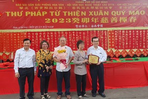 市祖国阵线委员会副主席刘金华（右二）、市各少数民族文学艺术协会副主席张四妹（左二）、华文《西贡解放日报》主编阮玉英（左一）向海南会馆赠送纪念章及鲜花以表谢意。