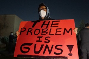 一名男子手持抗议枪枝暴力的标语牌。（图：新华社）
