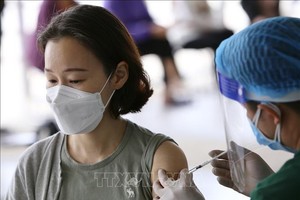 医务人员在为一名女性接种新冠疫苗。（图：越通社）