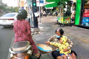 一名妇女携带着小孩呆在阮廷炤与阮善术街角口行乞。