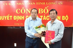 新闻与传播厅长阮伯伦（右）从隆安省人委会副主席阮明林手中接过人事委任《决定》和祝贺鲜花。（图：隆安报）