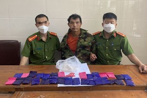 被抓获的毒贩禾柏哆（中）及冰毒物证。（图：越通社）