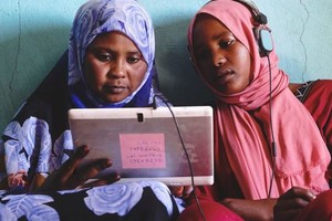 苏丹两名年轻女子在太阳能平板电脑上玩教育游戏。（图：儿基会）