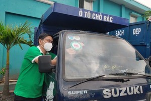 胡志明市都市环境一成员有限责任公司员工在楚鸡垃圾中转站给一辆垃圾收集车张贴管理标志。（图：潘秋怀）