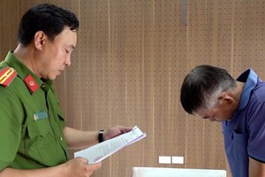 执法警员向犯罪嫌疑人黎文长宣读逮捕令。（图：安江报）