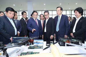 图为4月14日，范明政总理参观河内国立大学和乐实验室展示的微芯片制造产品。（图：越通社）