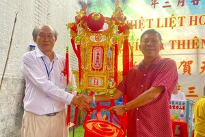 群宾会馆值理会主席曾业文（左）将第一圣灯移交得主黄英瑞，由父亲黄泽邦代领。