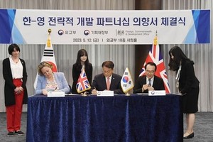 5月12日，在首尔外交部大楼，韩国企划财政部第一次官（副部长）方基善（中）、外交部第二次官李度勋（右）同到访的英国外交、联邦和发展事务部负责印太事务的国务大臣安妮-玛丽·特里维廉（左）签署《关于韩英建立战略发展合作关系的意向书》。（图：韩联社）