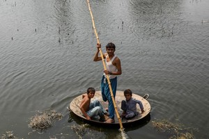 在巴基斯坦信德省，男孩们用一个大平底锅作为临时筏子趟过洪水。（图：联合国）