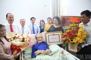 市委副书记阮胡海（左二）与代表们向张氏紫同志颁授65年党龄纪念章并赠送鲜花祝贺。（图：市党部新闻网）