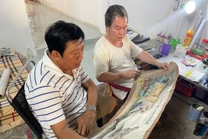 黄坤隆艺人（右）向老同学朱学光先生（左）介绍壁画稿。