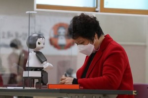 2020年11月16日，一名老人在韩国首尔阳川区一处老年福利文化中心利用数码教学机器人“LIKU”学习智能手机使用技能。（图：新华社）