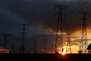 图为 2023年5月18日，在南非索韦托的奥兰多，由于燃煤电厂老化，南非公用事业公司 Eskom 经常停电，一名男子走在电线塔中。（图：路透社）