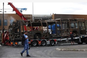 在巴黎以北的欧贝维利耶一处公交总站，工作人员将被示威者焚毁的公交车拖走。（图：互联网）