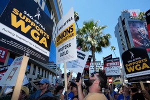 当地时间14日上午，在洛杉矶街头，美国演员工会-美国电视和广播艺人联合会宣布罢工，编剧组成的罢工纠察队在网飞工作室外集会，声援演员。（图：AP）