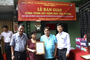 市越南祖国阵线委员会对外宣教处主任黎文秋（右一）和庆云南院住持周华邦（左一）向华人户移交“温情屋”工程。