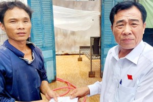 薄寮省和平县县委书记陈文渥（右）向受旋风影响的家庭发放辅助额。（图：红涛）