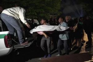 救援人员正在将死者遗体送往医院。（图：AFP）